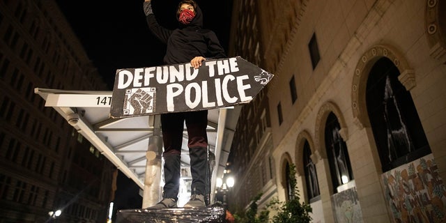 A protester holds a sign calling for the defunding of police at a protest on Saturday in Oakland, Calif. (AP Photo/Christian Monterrosa)