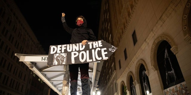 A protester holds a sign calling for the defunding of police at a protest on Saturday in Oakland, Calif. (AP Photo/Christian Monterrosa)