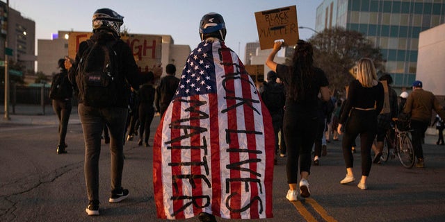 A protester wrapped in an American flag spray painted with 