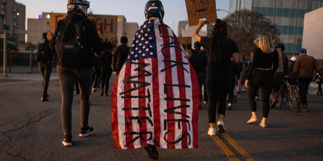 A protester wrapped in an American flag spray painted with 