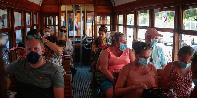 Tourists and locals ride a tram in town of Sóller in the Balearic Island of Mallorca, Spain, Monday, July 27, 2020. Britain has put Spain back on its unsafe list and announced Saturday that travelers arriving in the U.K. from Spain must now quarantine for 14 days. (AP Photo/Joan Mateu)