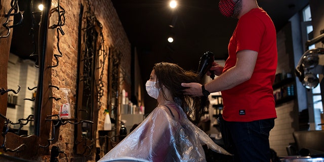 A woman, wearing a mask to protect against the spread of coronavirus, gets her hair styled in a hairdresser shop in downtown Brussels, Monday, July 27, 2020.  (AP Photo/Francisco Seco)