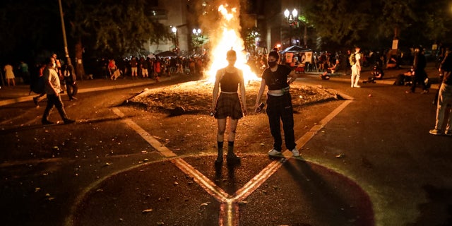 Demonstrators draw a peace sign in front of a fire during a Black Lives Matter protest at the Mark O. Hatfield United States Courthouse Tuesday, July 28, 2020, in Portland, Ore.