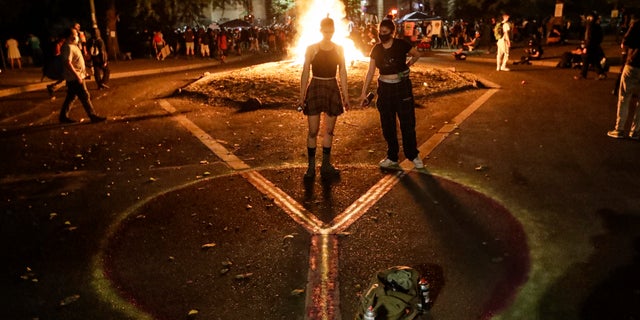 Demonstrators draw a peace sign in front of a fire during a Black Lives Matter protest at the Mark O. Hatfield United States Courthouse Tuesday, July 28, 2020, in Portland, Ore.