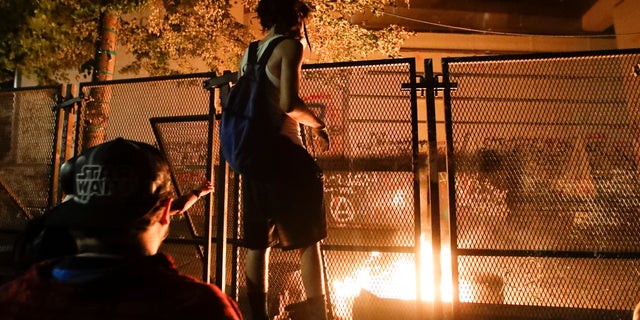 Demonstrators light a fire during a Black Lives Matter protest at the Mark O. Hatfield United States Courthouse Monday, July 27, 2020, in Portland, Ore. (AP Photo/Marcio Jose Sanchez)