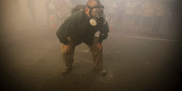 A demonstrator wears a gas mask as federal officers deploy tear gas during a Black Lives Matter protest at the Mark O. Hatfield United States Courthouse Monday in Portland, Ore. Several police agencies in Wisconsin have backed out of sending officers to next month's Democratic National Convention in response to local orders preventing the use of tear gas to control crowds. 