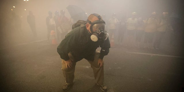 A demonstrator wears a gas mask as federal officers deploy tear gas during a Black Lives Matter protest at the Mark O. Hatfield United States Courthouse Monday in Portland, Ore. Several police agencies in Wisconsin have backed out of sending officers to next month's Democratic National Convention in response to local orders preventing the use of tear gas to control crowds. 