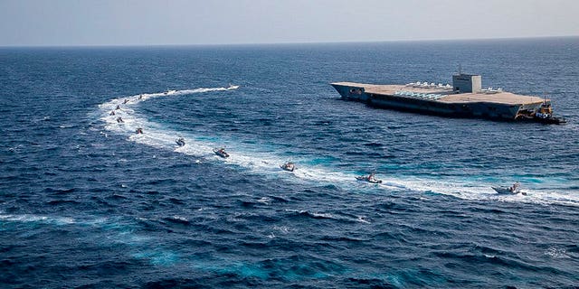 Revolutionary Guard's speed boats circle around a replica American aircraft carrier during a military exercise. (Sepahnews via AP)