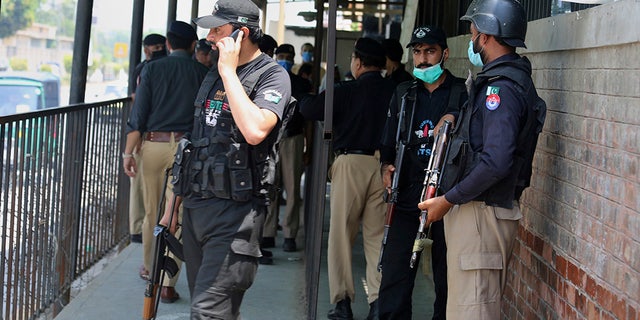 Police officers gather at an entry gate of district court following the killing of Tahir Ahmad Naseem, who was in court accused of insulting Islam, in Peshawar, Pakistan, Wednesday, July 29, 2020. (AP Photo/Muhammad Sajjad)