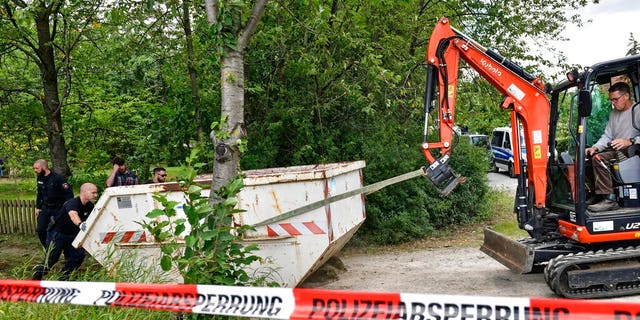 Germany police officers remove a container during a search at an allotment garden plot in Seelze, near Hannover, Germany, Wednesday, July 29, 2020. Police have begun searching an allotment garden plot, believed to be in connection with the 2007 Portugal disappearance of missing British girl Madeleine McCann. (AP Photo/Martin Meissner)