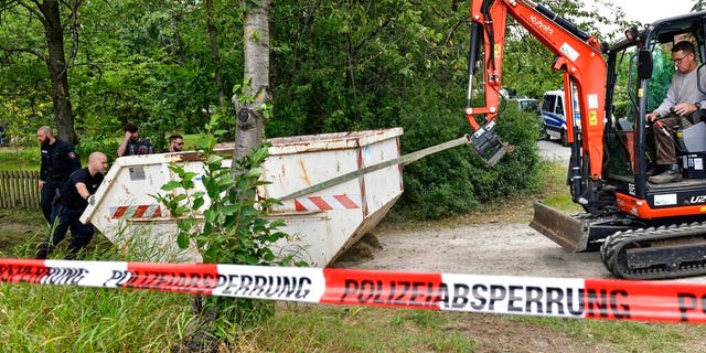 Germany police officers remove a container during a search at an allotment garden plot in Seelze, near Hannover, Germany, Wednesday, July 29, 2020. Police have begun searching an allotment garden plot, believed to be in connection with the 2007 Portugal disappearance of missing British girl Madeleine McCann. (AP Photo/Martin Meissner)