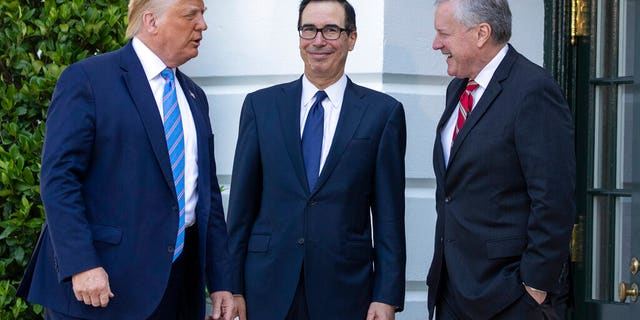 President Donald Trump, Treasury Secretary Steven Mnuchin, White House Chief of Staff Mark Meadows talk before Trump speaks with reporters on the South Lawn of the White House, Wednesday, July 29, 2020, in Washington. Trump is en route to Texas. (AP Photo/Alex Brandon)