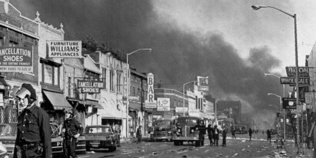 July 24, 1967: Police check buildings along a section of 12th Street, about three miles from downtown Detroit, following racial riots which broke out in the city. Many businesses and homes were burned and looted. (AP Photo/File)