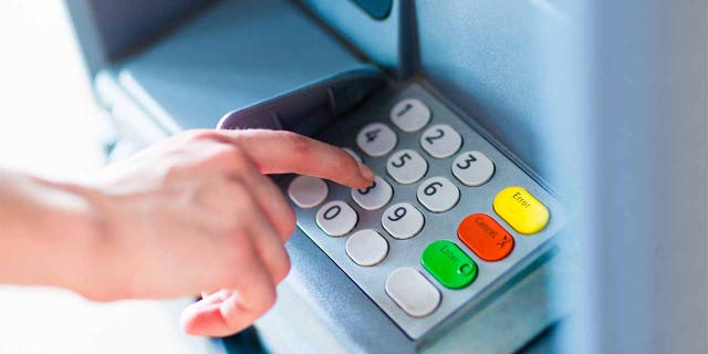 Close-up of hand entering PIN/pass code for a money transfer, on a ATM/bank machine keypad - file photo.