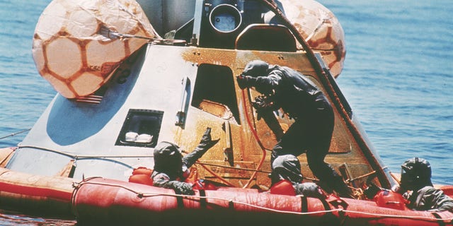 U.S. Navy personnel, protected by Biological Isolation Garments, are recovering the Apollo 11 crew from a re-entry vrehicle, which landed safely in the Pacific Ocean on July 24, 1969, after an eight-day mission on the moon. (AP Photo)