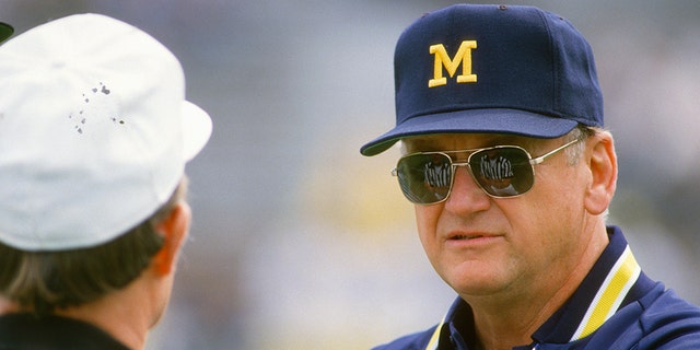 Head Coach Bo Schembechler of the Michigan Wolverines talks with an official while his team warms up before the start of an NCAA football game circa 1986.