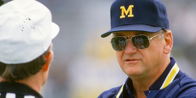 Head Coach Bo Schembechler of the Michigan Wolverines talks with an official while his team warms up before the start of an NCAA football game circa 1986.