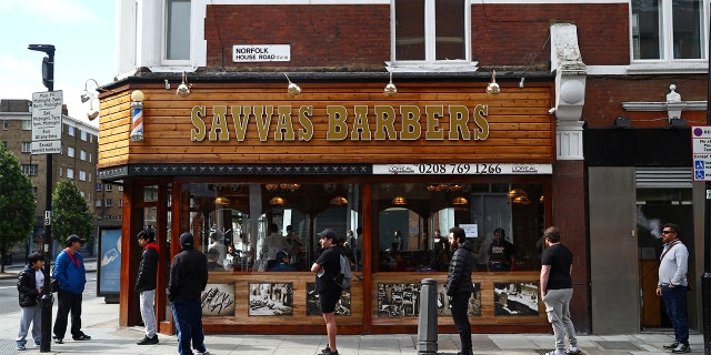 People queue outside Savvas Barbers as it reopened following the outbreak of the coronavirus disease (COVID-19), in London, Britain July 4, 2020. REUTERS/Hannah McKay - RC28MH94GQPU