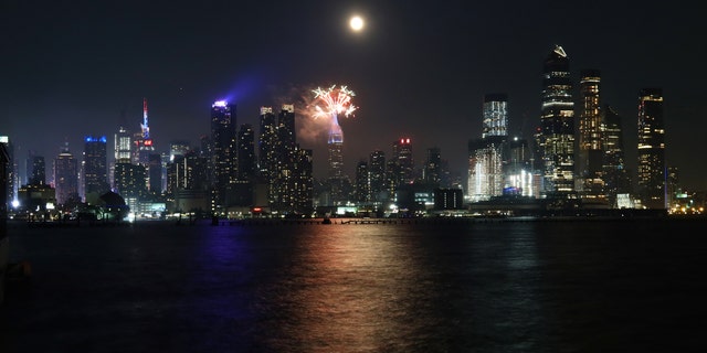 Macy's fireworks go off on the top of the Empire State Building as the full buck moon rises in the sky on July 4, 2020 as seen from Weehawken, New Jersey.