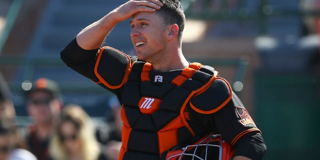 San Francisco Giants catcher Buster Posey wipes sweat from his forehead during the first inning of a 2020 spring training game against the Arizona Diamondbacks in Scottsdale, Ariz.