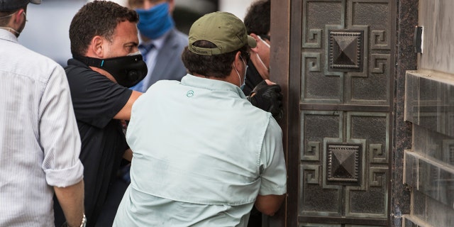 Federal officials and a locksmith pull on a door to make entry into the vacated Consulate General of China building Friday, July 24, 2020, in Houston. On Tuesday, the U.S. ordered the Houston consulate closed within 72 hours, alleging that Chinese agents had tried to steal data from facilities in Texas, including the Texas A&M medical system and The University of Texas MD Anderson Cancer Center in Houston.