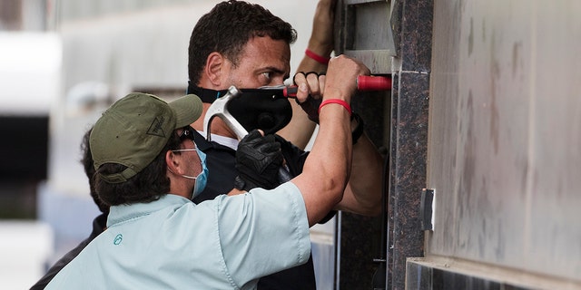 Federal officials and a locksmith work on a door to make entry into the vacated Consulate General of China building Friday, July 24, 2020, in Houston. On Tuesday, the U.S. ordered the Houston consulate closed within 72 hours, alleging that Chinese agents had tried to steal data from facilities in Texas, including the Texas A&M medical system and The University of Texas MD Anderson Cancer Center in Houston. (Brett Coomer/Houston Chronicle via AP)