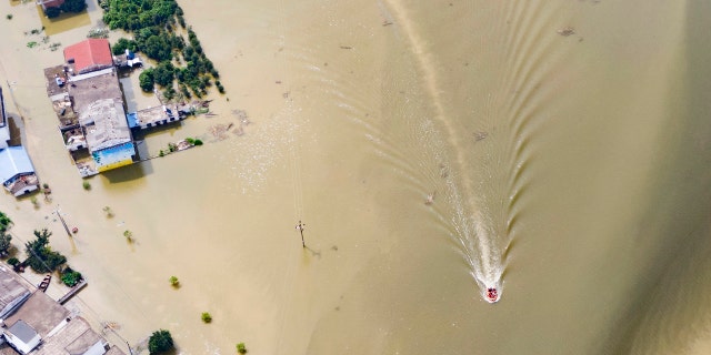 In this aerial photo released by Xinhua News Agency, rescue workers on a raft are seen moving through flood waters to help evacuate trapped residents in Sanjiao Township of Yongxiu County in central eastern China's Jiangxi Province on Monday, July 13, 2020.