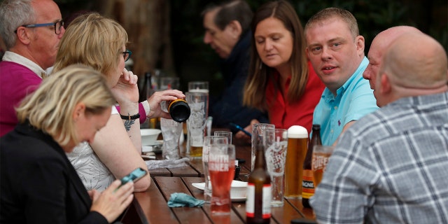 People enjoy their drinks at the beer garden of the Forester pub in London, Saturday, July 4, 2020. England is embarking on perhaps its biggest lockdown easing yet as pubs and restaurants have the right to reopen for the first time in more than three months. In addition to the reopening of much of the hospitality sector, couples can tie the knot once again, while many of those who have had enough of their lockdown hair can finally get a trim. (AP Photo/Frank Augstein)