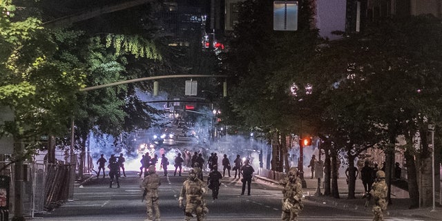 Authorities gather in the street amid protests in Portland. Ore.