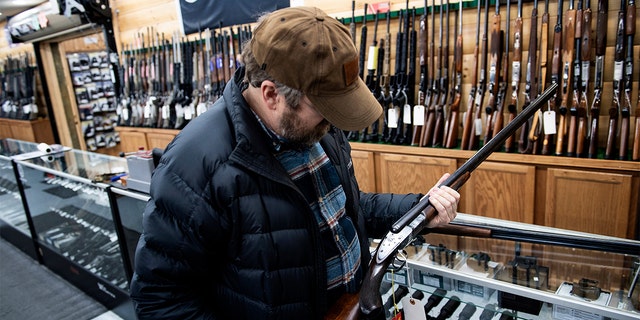 A customer looks at an antique shotgun. (Brendan Smialowski / AFP)