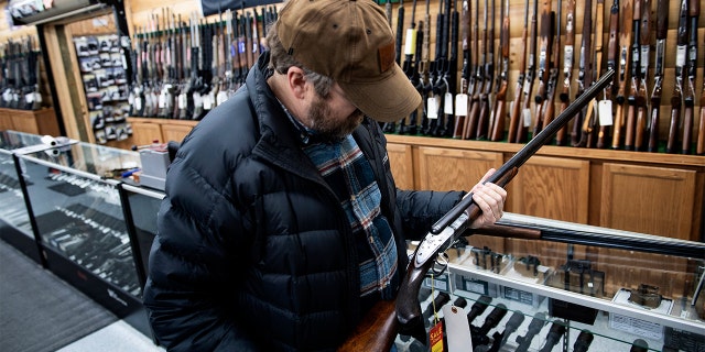 A customer looks at an antique shotgun. (Brendan Smialowski / AFP)