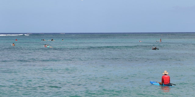 A paddler sits off Waikiki Beach in Honolulu, Saturday, July 25, 2020, as Hurricane Douglas approaches.