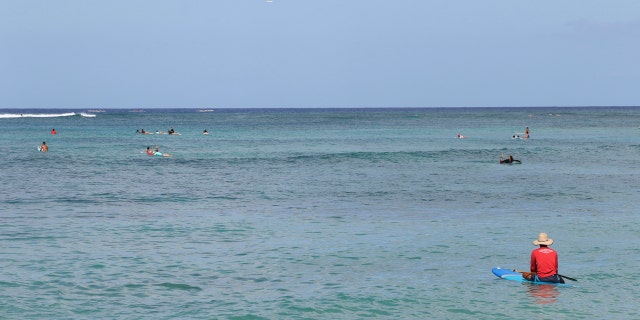 A paddler sits off Waikiki Beach in Honolulu, Saturday, July 25, 2020, as Hurricane Douglas approaches.