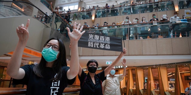 Protesters show a banner "Librate Hong Kong, Revolution of our time" in a shopping mall during a protest in Hong Kong in June. The slogan had just been banned by the government under the new legislation, stating that it had separatist connotations. (AP)