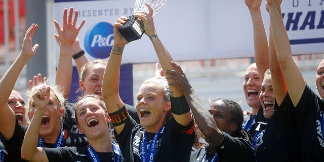 Houston Dash forward Rachel Daly holds the trophy alongside teammates as they celebrate their Challenge Cup championship win over the Chicago Red Stars, Sunday, July 26, 2020, in Sandy, Utah. (AP Photo/Rick Bowmer)