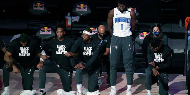 Orlando Magic's Jonathan Isaac (1) stands as others kneel before the start of an NBA basketball game between the Brooklyn Nets and the Orlando Magic Friday, July 31, 2020, in Lake Buena Vista, Fla. (AP Photo/Ashley Landis, Pool)