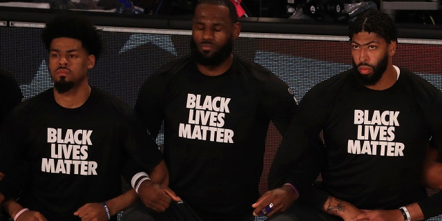 Los Angeles Lakers' LeBron James, center, wears a Black Lives Matter shirt and kneels with teammates during the national anthem prior to an NBA basketball game against the Los Angeles Clippers, Thursday, July 30, 2020, in Lake Buena Vista, Fla. (Associated Press)