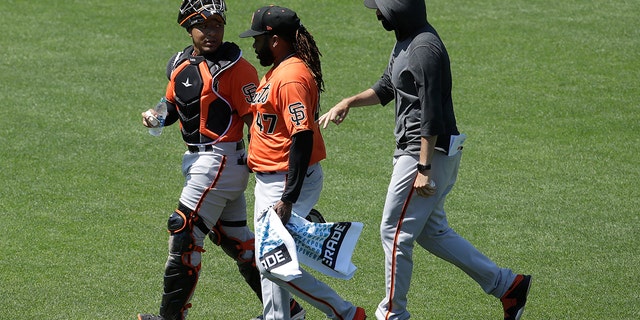 San Francisco Giants' Chadwick Tromp, left, walks with Johnny Cueto, center, and another player during baseball practice in San Francisco, Tuesday, July 14, 2020. (AP Photo/Jeff Chiu)