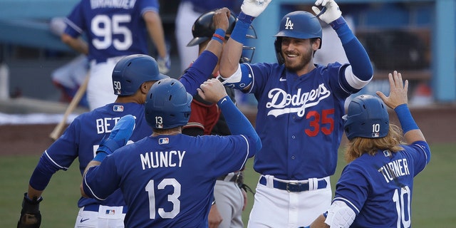 Los Angeles Dodgers' Cody Bellinger (35) is met at home plate after hitting a grand slam during the first inning of an exhibition baseball game against the Arizona Diamondbacks Sunday, July 19, 2020, in Los Angeles. (AP Photo/Marcio Jose Sanchez)