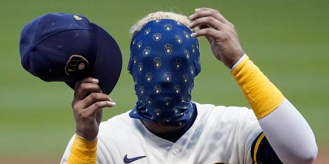 Milwaukee Brewers' Orlando Arcia covers his face with his mask during an intrasquad game Tuesday, July 14, 2020, at Miller Park in Milwaukee. (AP Photo/Morry Gash)