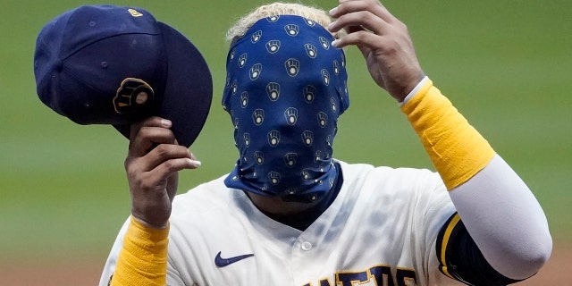 Milwaukee Brewers' Orlando Arcia covers his face with his mask during an intrasquad game Tuesday, July 14, 2020, at Miller Park in Milwaukee. (AP Photo/Morry Gash)