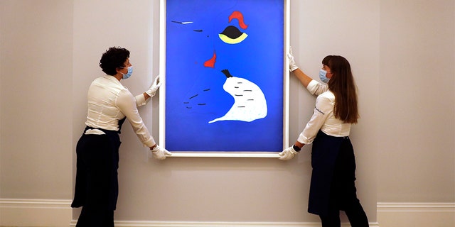 In this Thursday, July 23, 2020 file photo, Sotheby employees adjust a painting by Joan Miro called 'Peinture (Femme au chapeau rouge) at Sotheby's auction rooms in London. Miró’s “Peinture (Femme au chapeau rouge)” (Woman in a Red Hat) from 1927. (AP Photo/Kirsty Wigglesworth, File)