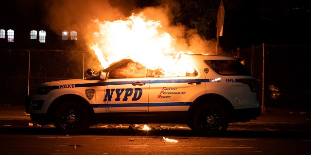 An NYPD police car is set on fire as protesters clash with police during a march against the death in Minneapolis police custody of George Floyd, in the Brooklyn borough of New York City, U.S., May 30, 2020. (REUTERS/Jeenah Moon)