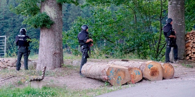 경찰관들은 2020 년 7 월 13 일 월요일 독일 Oppenau 근처 도로의 숲이 우거진 지역 밖에 머물고 있습니다. 독일 당국은 31 세의 남자를 위해 총 3 명의 경찰관을 무장 해제 한 수백 명의 경찰을 배치했다고 밝혔습니다. 2020 년 7 월 12 일 일요일. (AP를 통한 Sven Kohls / dpa)