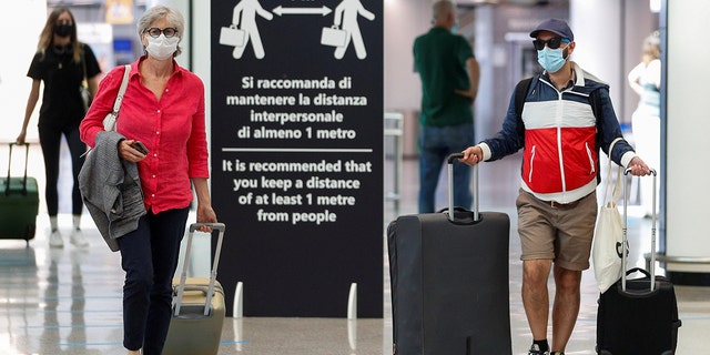 Passengers wearing protective face masks walk at Fiumicino Airport on the day EU governments agreed a "safe list" of 14 countries for which they will allow non-essential travel starting from July, following the coronavirus disease (COVID-19) outbreak, in Rome, Italy, June 30, 2020. (REUTERS/Guglielmo Mangiapane)