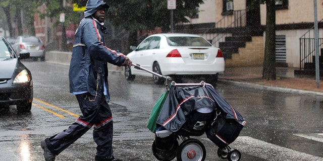 A United States Postal Service (USPS) mail carrier walks through heavy rain as Tropical Storm Fay sweeps across the heavily populated northeastern United States in Jersey City, New Jersey, U.S., July 10.