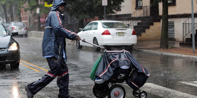 A United States Postal Service (USPS) mail carrier walks through heavy rain as Tropical Storm Fay sweeps across the heavily populated northeastern United States in Jersey City, New Jersey, U.S., July 10.  