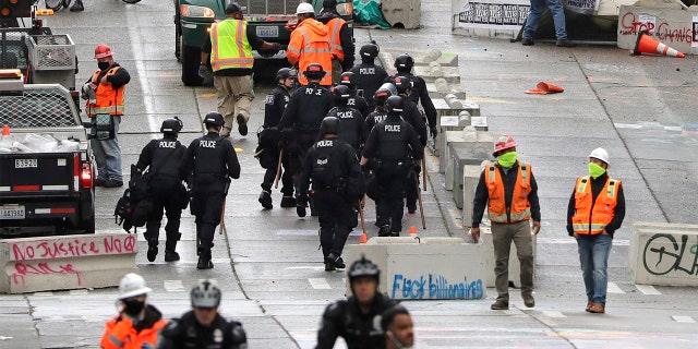 Police and city workers fill a street occupied hours earlier by an encampment of protesters Wednesday, July 1, 2020, in Seattle, where streets had been blocked off in an area demonstrators had occupied for weeks.