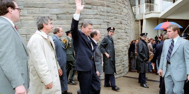 Ronald Reagan waves just moments before he was shot on March 30, 1981. Secret Service Tim McCarthy is on the right in the photo, wearing a business suit and striped tie.