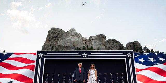 President Donald Trump, accompanied by first lady Melania Trump, stand during a flyover at Mount Rushmore National Memorial, Friday, July 3, 2020, near Keystone, S.D. (AP Photo/Alex Brandon)